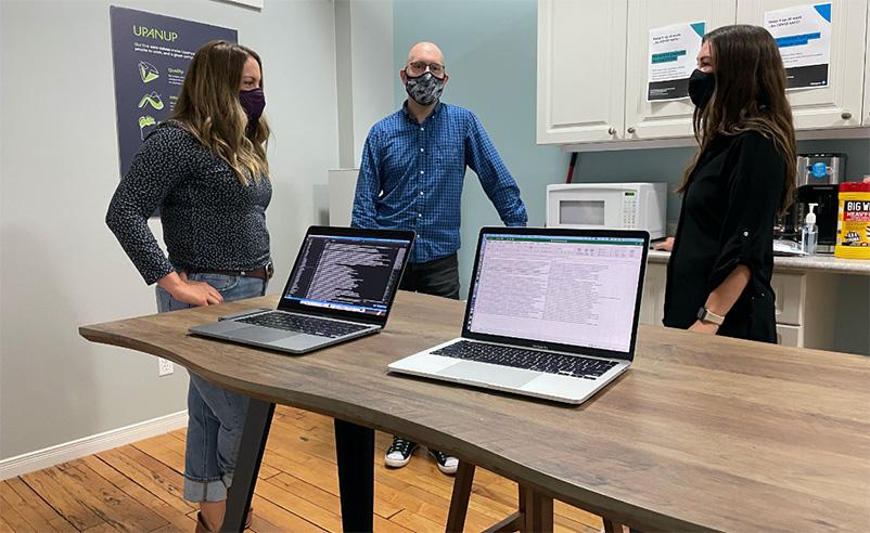 Discussion between three team members with two laptops on the table
